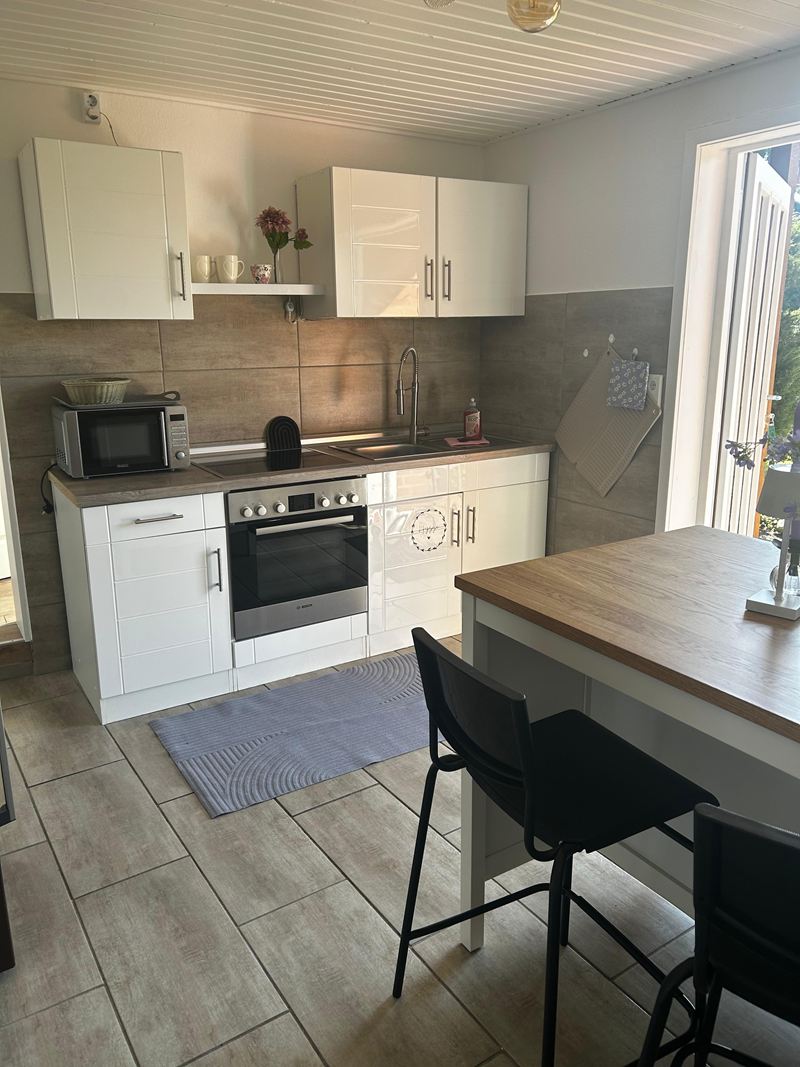 Küche mit Backofen, Mikrowelle und Theke mit Barhockern in der Ferienwohnung Lilit