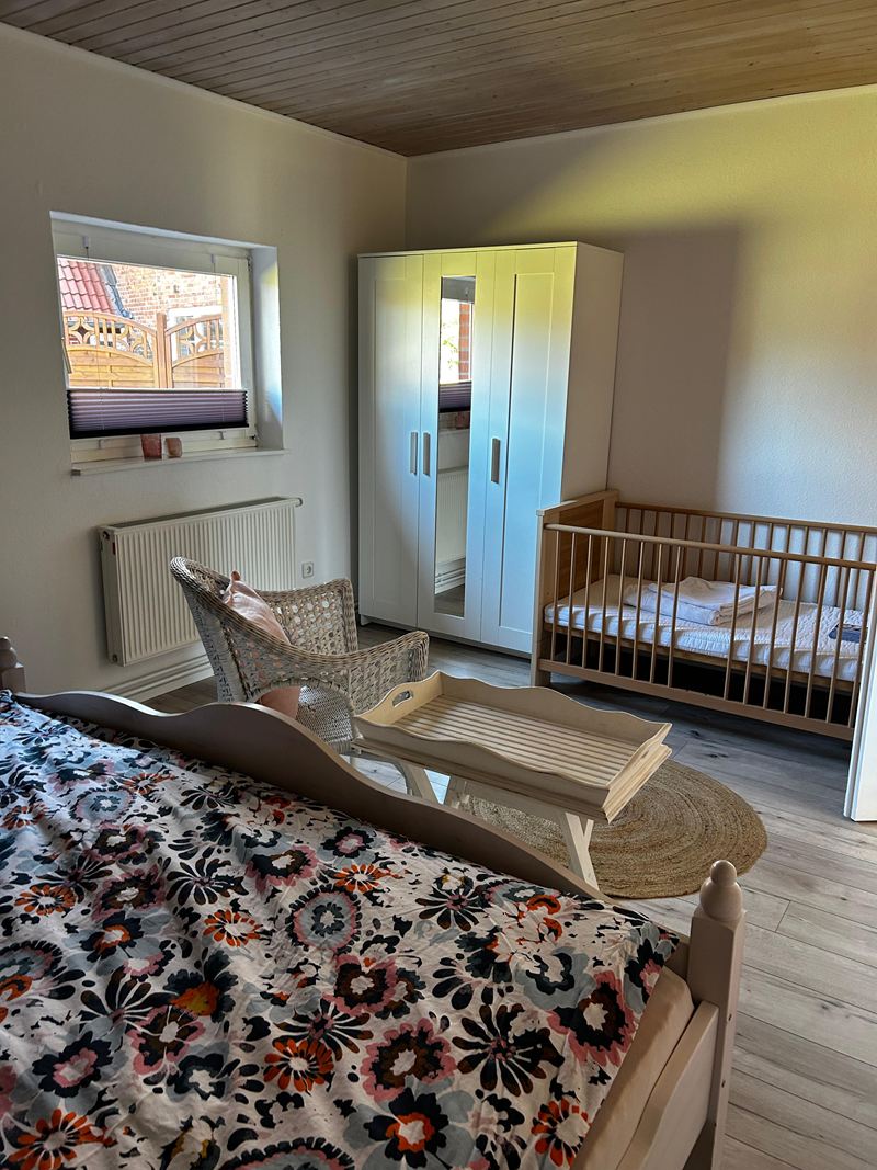 Schlafzimmer mit Babybett und Kleiderschrank in der Ferienwohnung Lilit