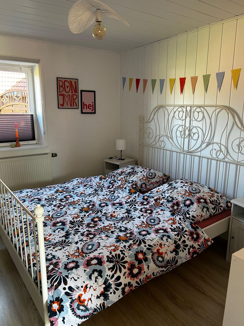 Schlafzimmer mit weißem Metallbett und Wimpelkette in der Ferienwohnung Lilit
