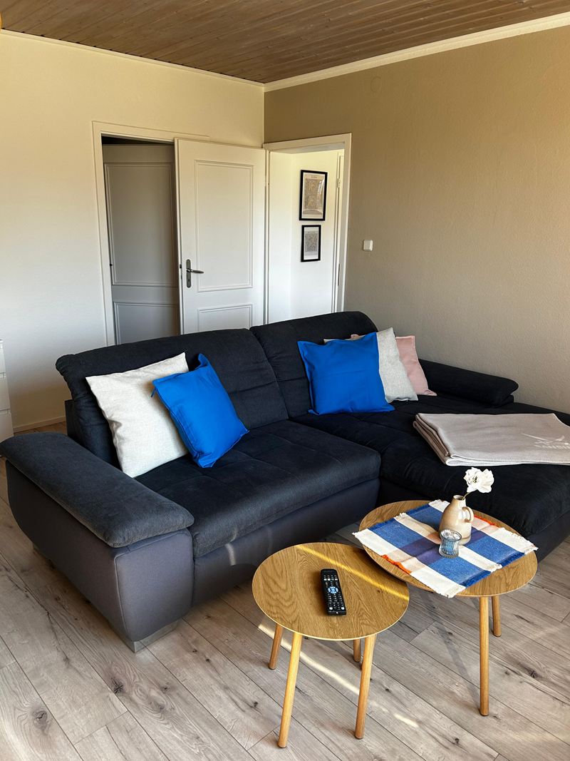 Wohnzimmer mit dunklem Ecksofa und Couchtischen in der Ferienwohnung Lilit
