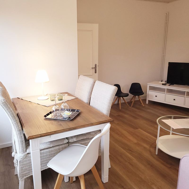 Essbereich mit Holztisch und Blick in den Wohnbereich der Ferienwohnung Lotta