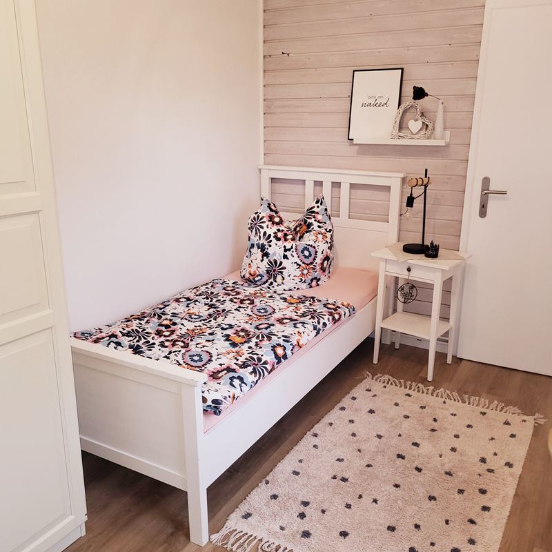 Schlafzimmer mit Einzelbett und Nachttisch in der Ferienwohnung Lotta