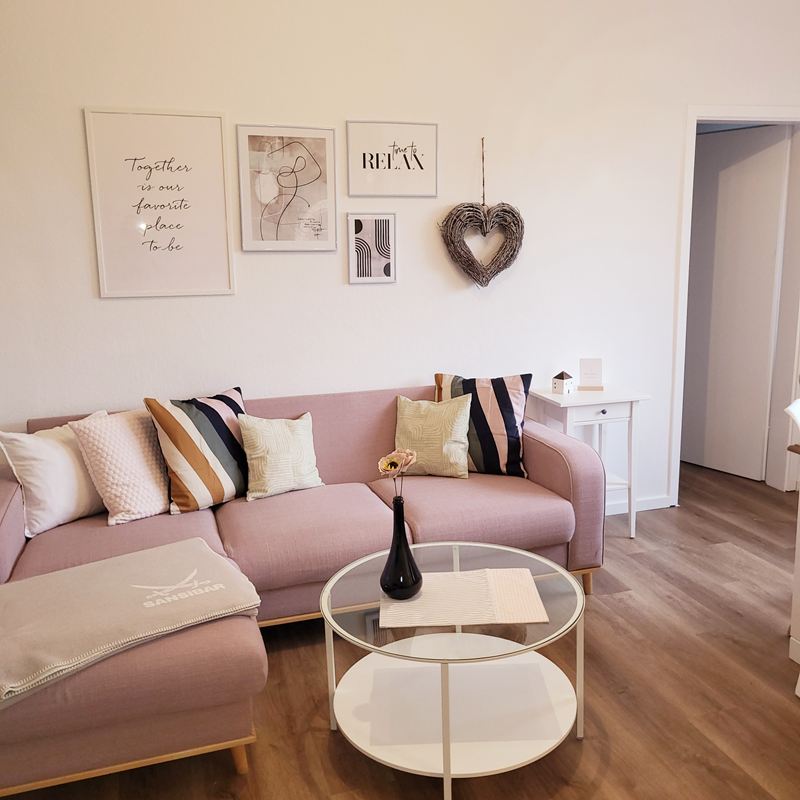 Wohnzimmer mit Ecksofa und rundem Glastisch in der Ferienwohnung Lotta
